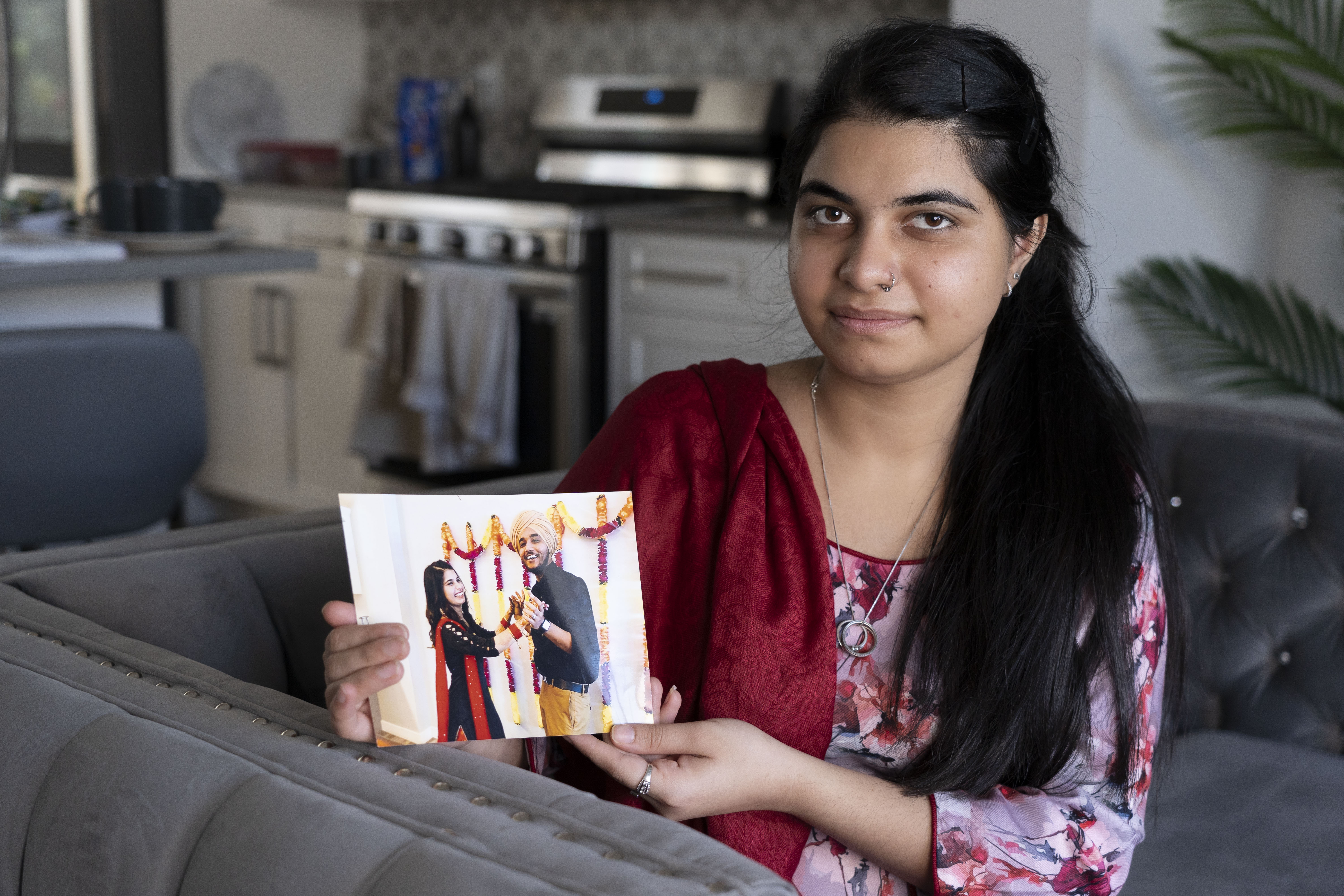 A young girl sits down while she holds a photo of a wedding couple.